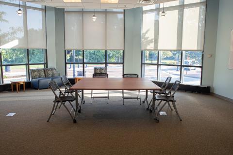 Octagon room shaped like an octagon with two conference tables pushed together and chairs around the table with extra seating lined against the walls