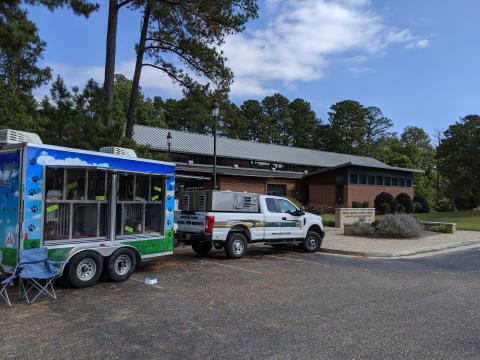 a truck and trailer sit in front of the PG library, the trailer has windows and inside the windows are dogs