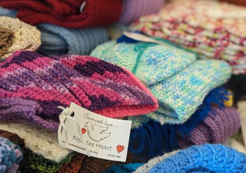 a pile of knitted and crocheted items with a while label with a dove attached